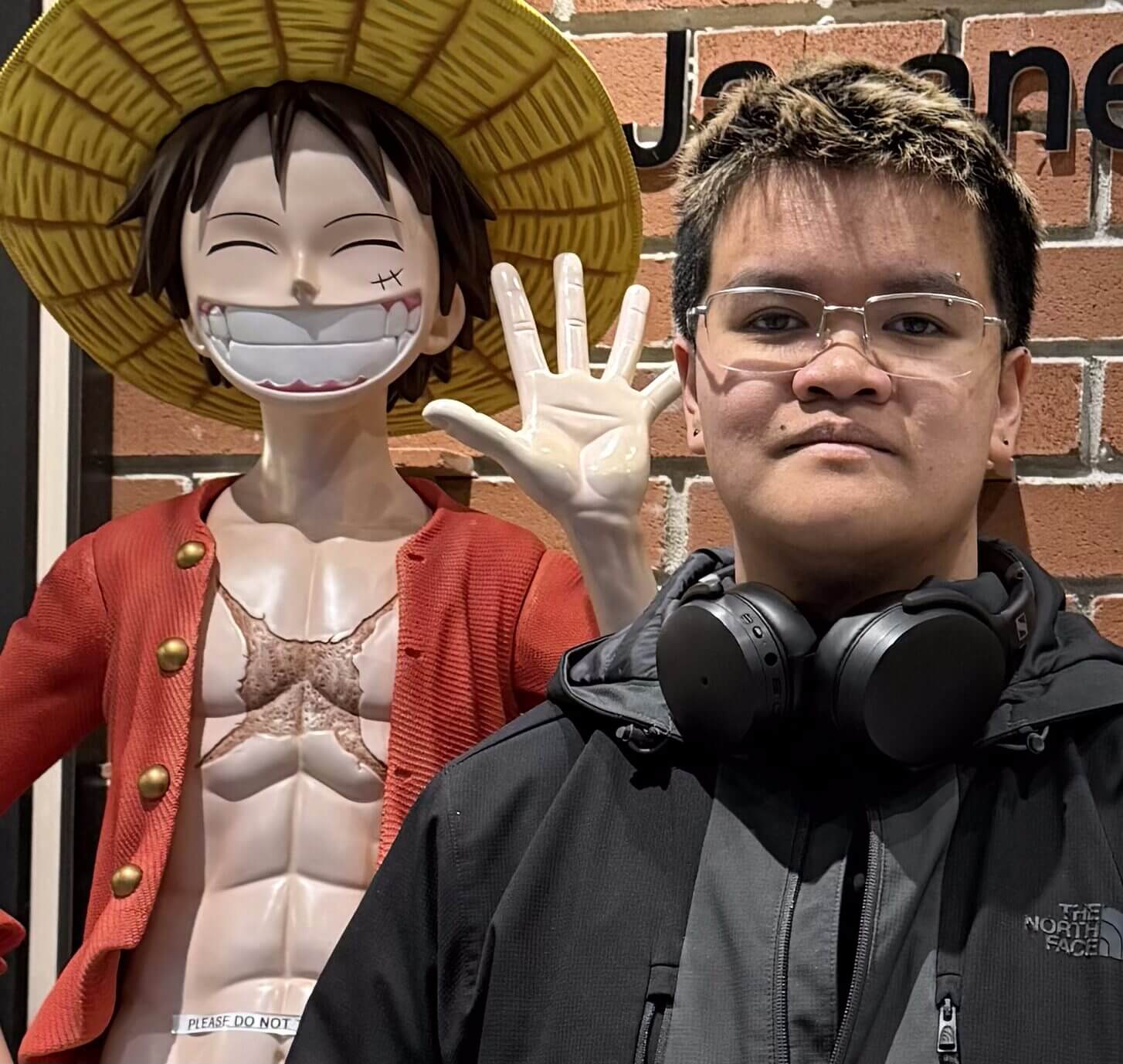 Person with headphones beside smiling anime statue