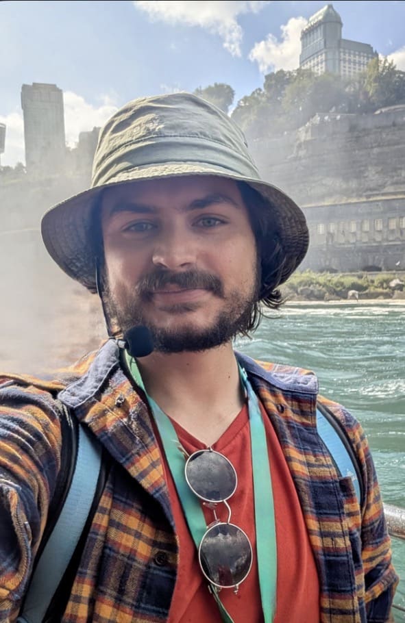 Person with bucket hat by waterfall and river