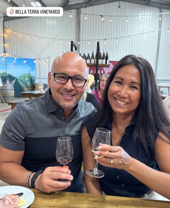 Smiling couple toasting with wine at vineyard