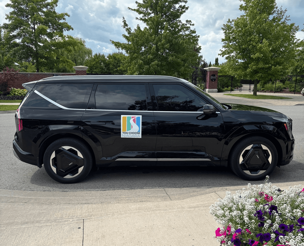 Black SUV parked by curb with flowers