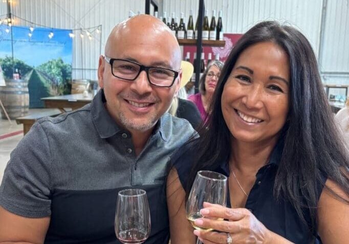 Smiling couple toasting with wine at vineyard